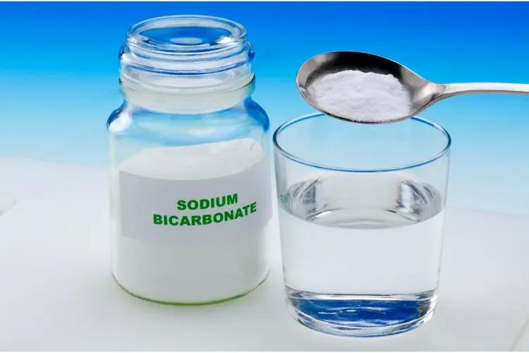 Du bicarbonate de soude à côté d'un verre de vinaigre