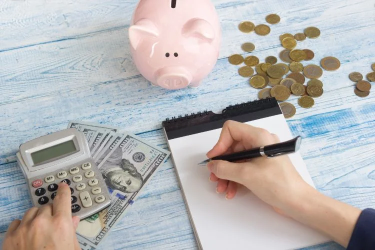 Une personne avec une tirelire et une calculatrice qui calcule son budget.