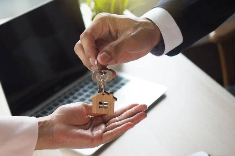 Un vendeur immobilier qui donne les clé du logement au nouveau propriétaire.