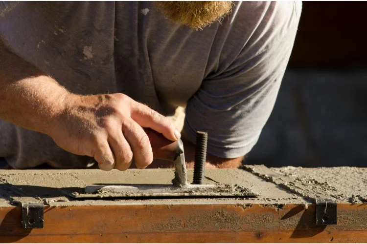 Un homme qui pose de l'enduit de finition à l'aide d'une lisseuse sur du béton