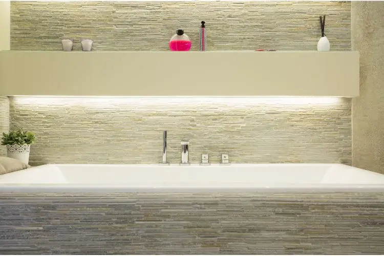 Salle de bain lumineuse, avec un éclairage à côté de la baignoire.
