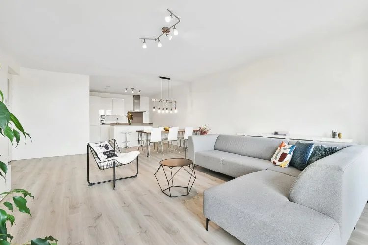 Un salon spacieux dans des tons clairs avec un grand canapé d'angle gris