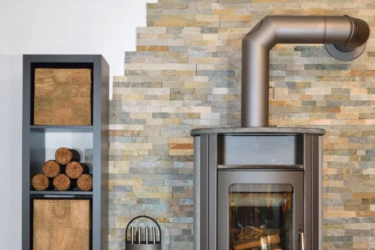 Un poêle à bois moderne avec un mur recouvert de parement en pierre asymétrique.