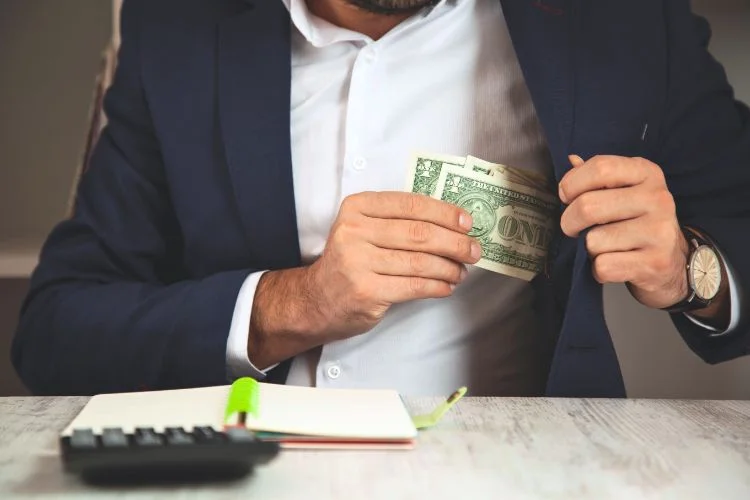 Un homme d'affaires qui cache de l'argent liquide dans sa veste.